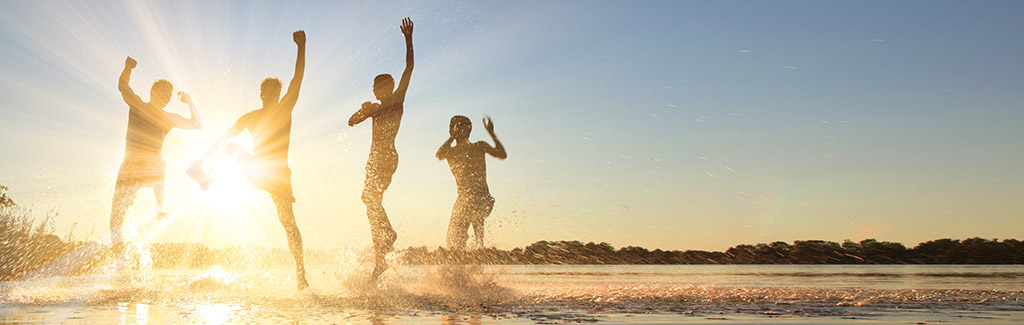 Kinder springen im Wasser bei hellen Sonnenschein