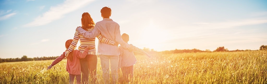 Familie steht im Feld und schaut zur Sonne