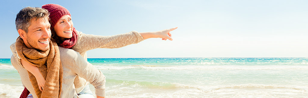 Mann hat seine Frau huckepack am Strand